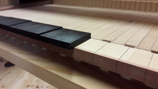 Auf der Oberseite werden die vorderen Untertastenbeläge aus Ebenholz in einen Falz eingesetzt